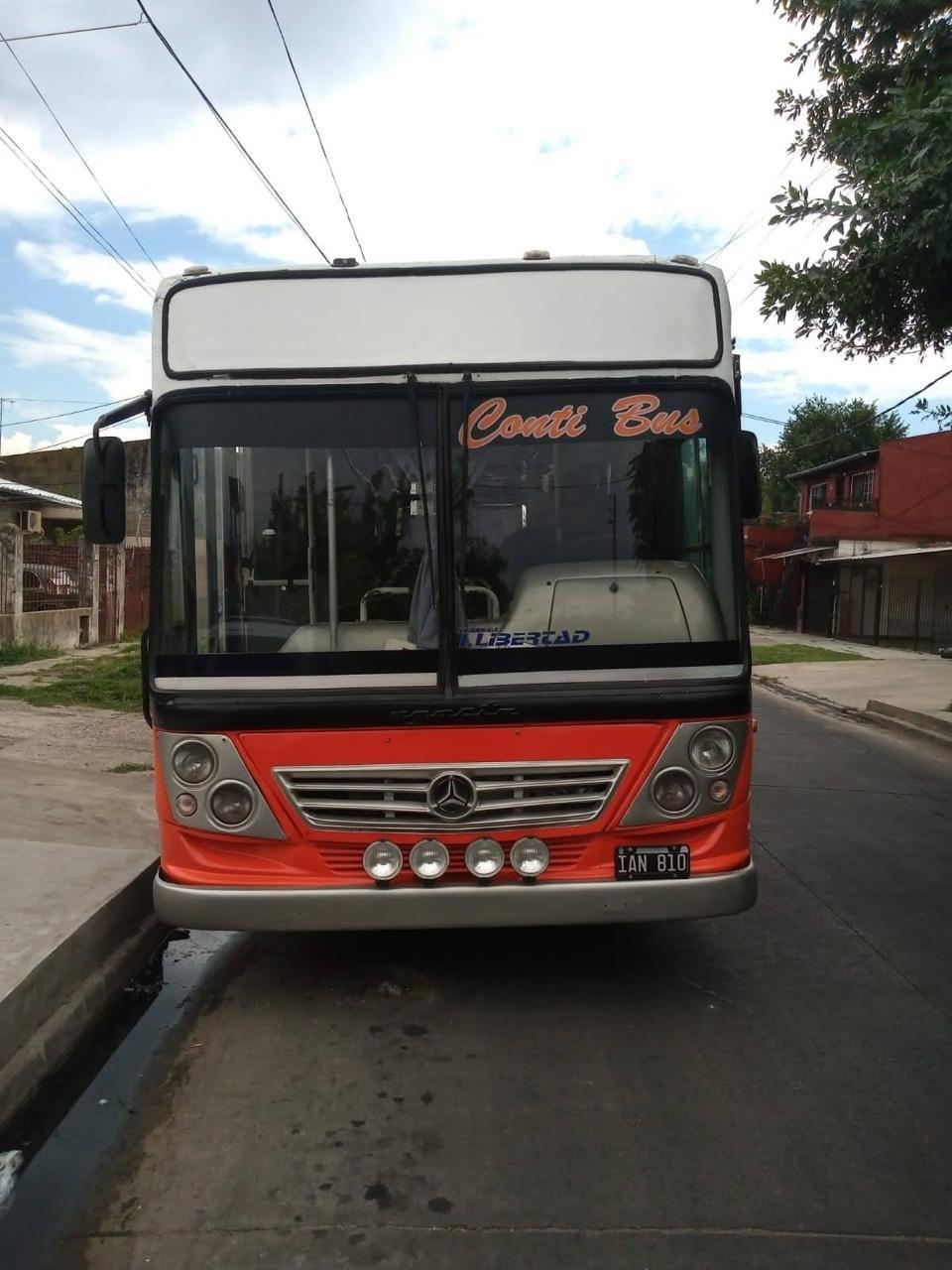 Frente de un micro rojo y blanco de Conti Bus estacionado en una calle de barrio