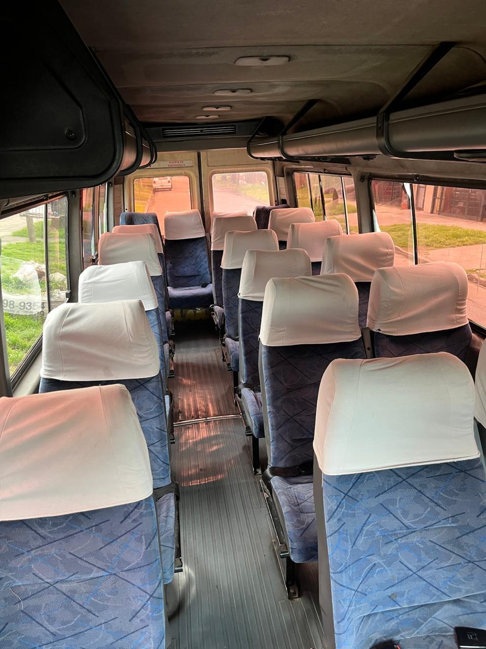 Interior de una camioneta con asientos tapizados en azul y fundas blancas en los cabezales